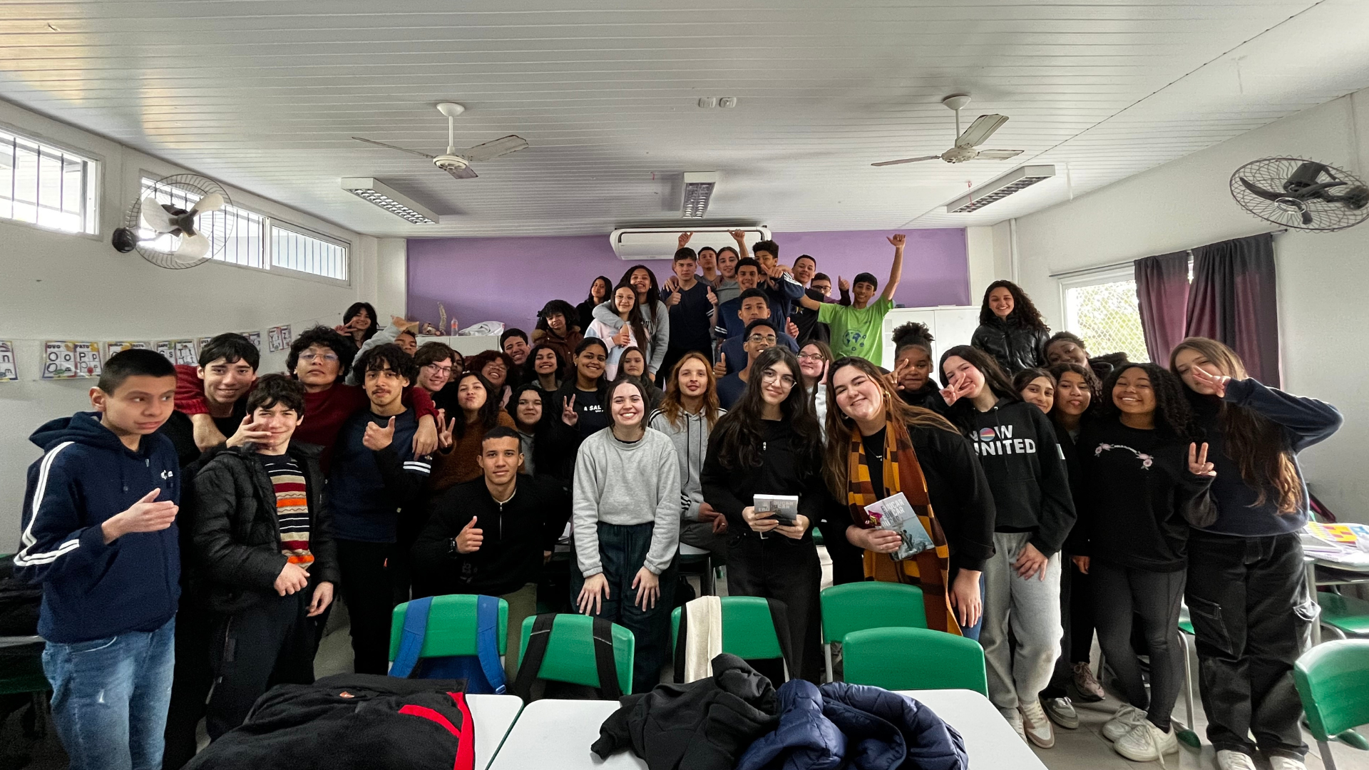 Foto de um grupo de estudantes reunidos em uma sala de aula, posando para a câmera.